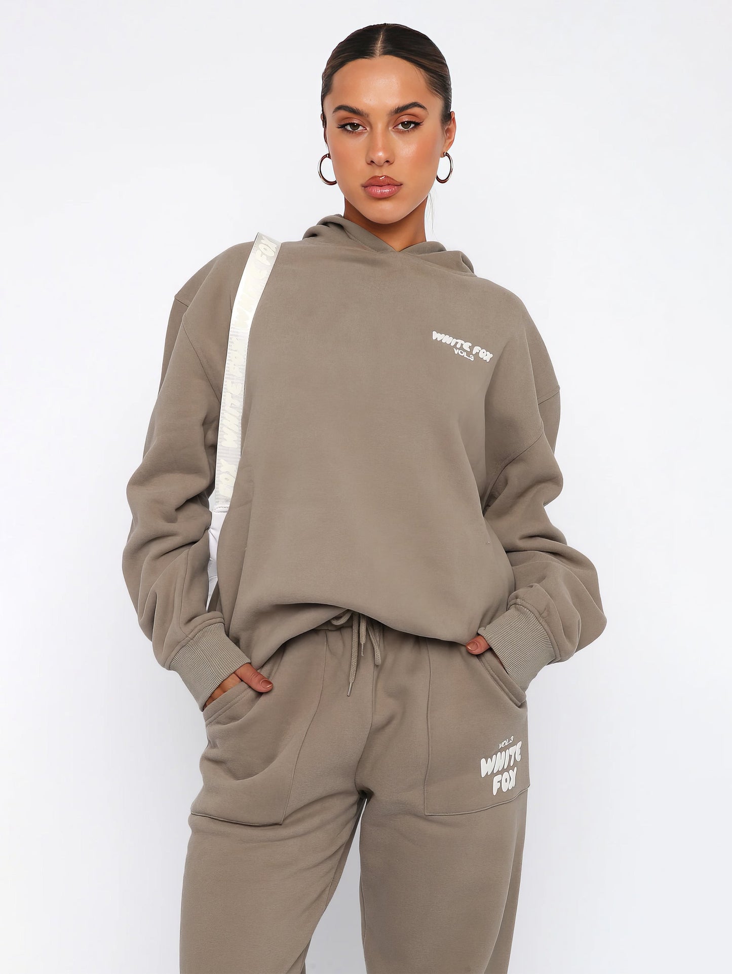 "Dames trainingspak met oversized pasvorm, wit, elastische ribboorden, trendy puffprint logo en fleecestof."
