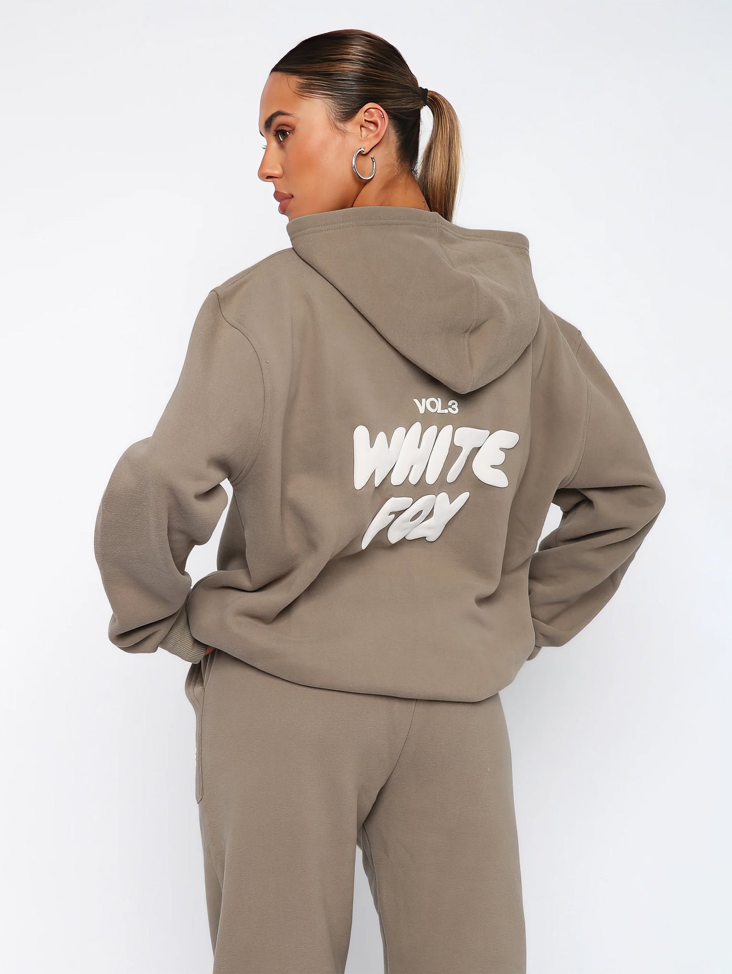 "Dames trainingspak met oversized pasvorm, wit, elastische ribboorden, trendy puffprint logo en fleecestof."