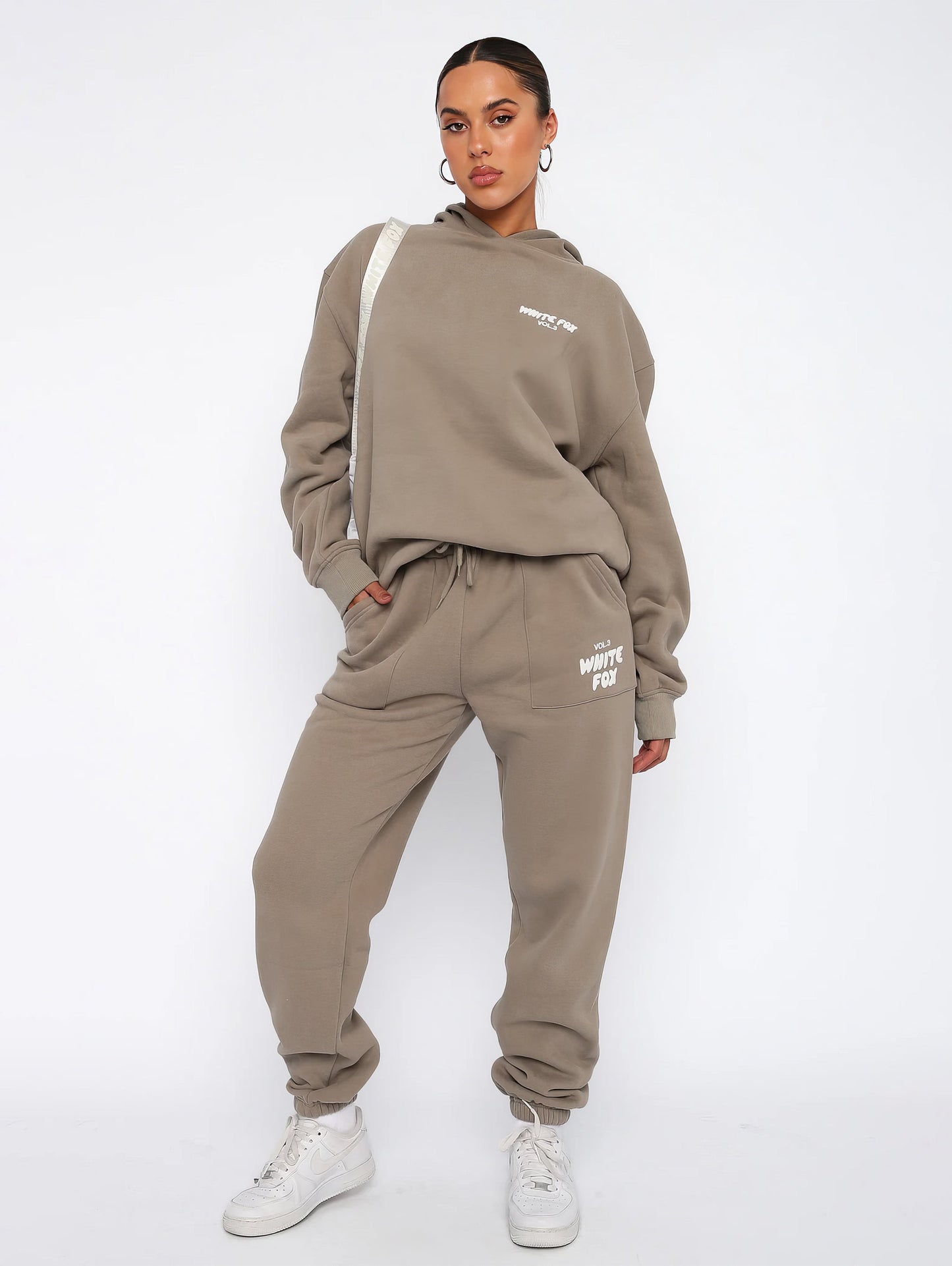 "Dames trainingspak met oversized pasvorm, wit, elastische ribboorden, trendy puffprint logo en fleecestof."