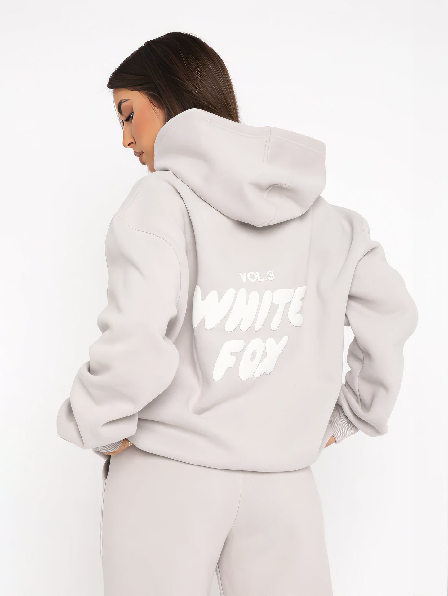 "Dames trainingspak met oversized pasvorm, wit, elastische ribboorden, trendy puffprint logo en fleecestof."