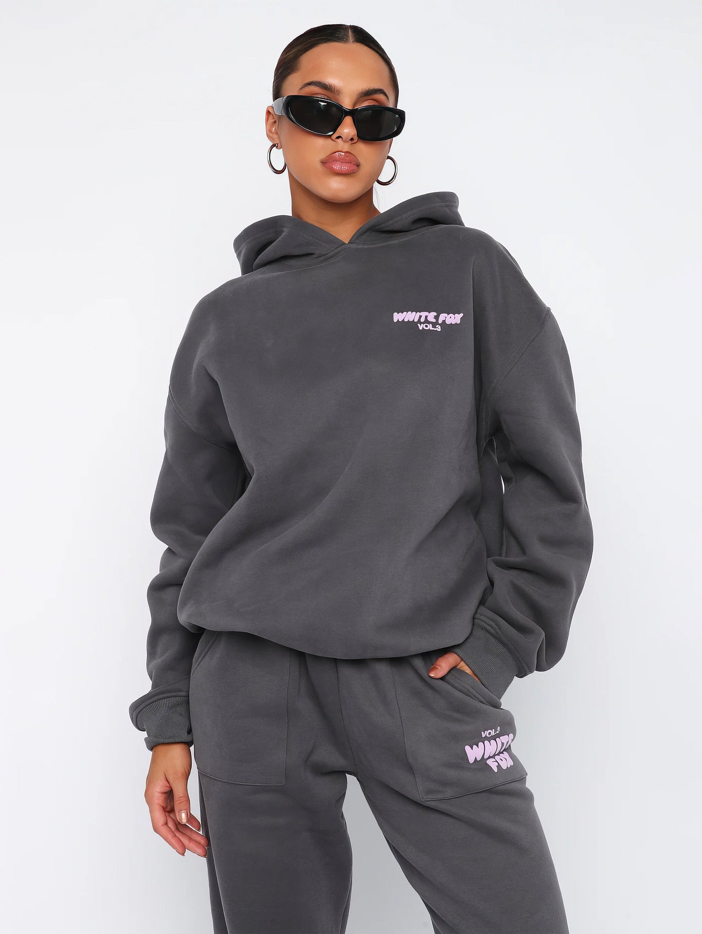 "Dames trainingspak met oversized pasvorm, wit, elastische ribboorden, trendy puffprint logo en fleecestof."
