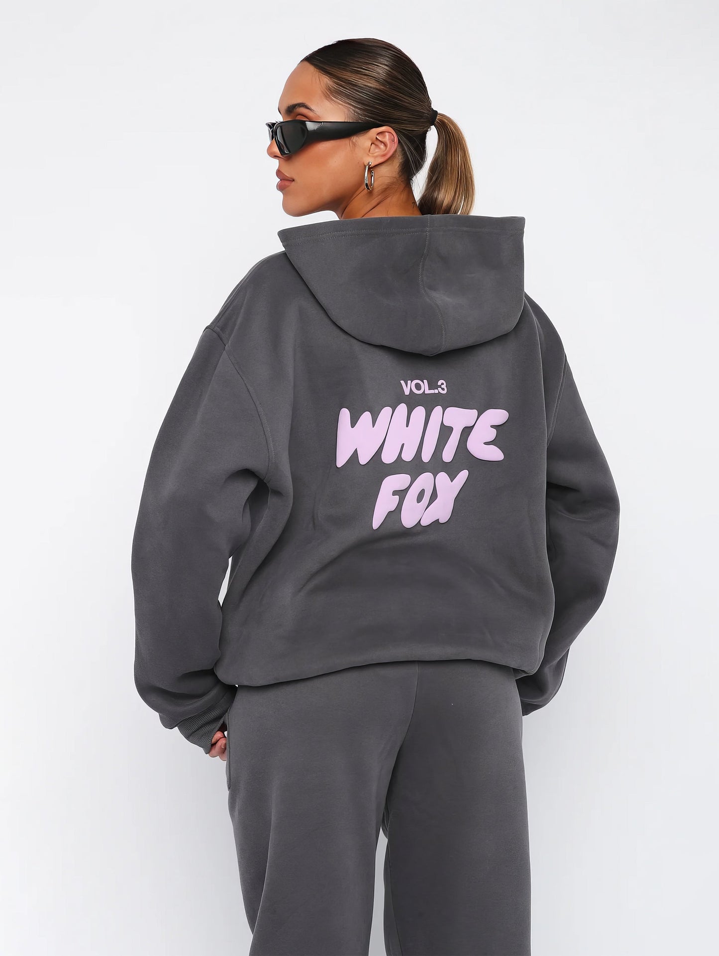 "Dames trainingspak met oversized pasvorm, wit, elastische ribboorden, trendy puffprint logo en fleecestof."