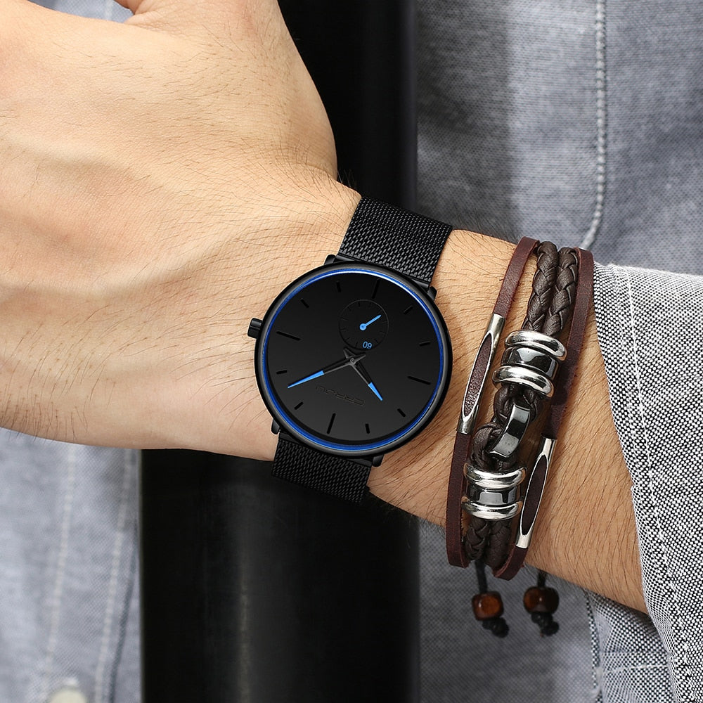 "Dun minimalistisch herenhorloge met elegante zwarte wijzerplaat, roestvrijstalen mesh-band en luxe uitstraling."