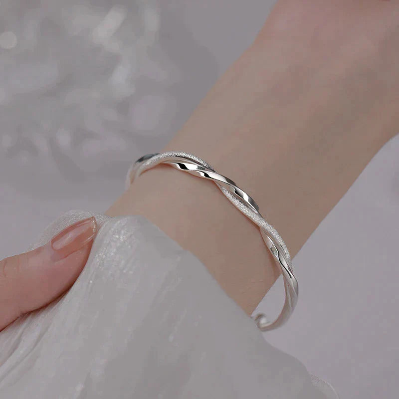 "Elegant gedraaide zilveren armband, verstelbaar, met gedetailleerd ontwerp. Perfect voor elke gelegenheid."