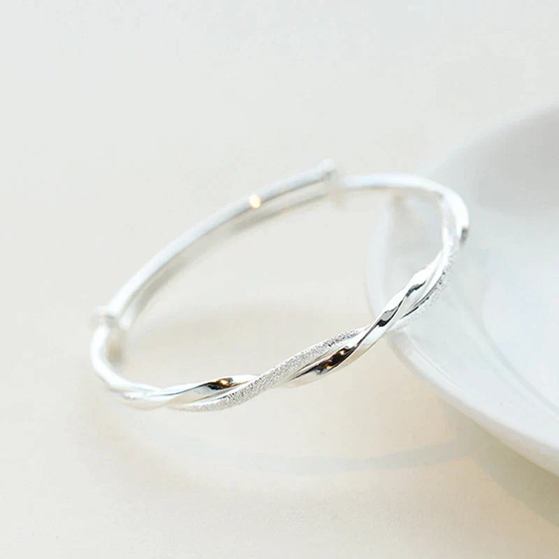 "Elegant gedraaide zilveren armband, verstelbaar, met gedetailleerd ontwerp. Perfect voor elke gelegenheid."
