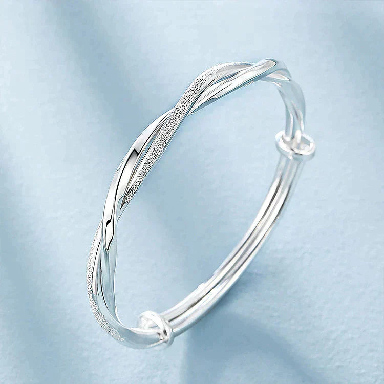 "Elegant gedraaide zilveren armband, verstelbaar, met gedetailleerd ontwerp. Perfect voor elke gelegenheid."