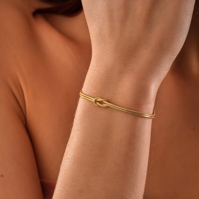 "Elegant gouden liefdesknoop armband voor dames, minimalistisch ontwerp, tijdloos en verfijnd accessoire."