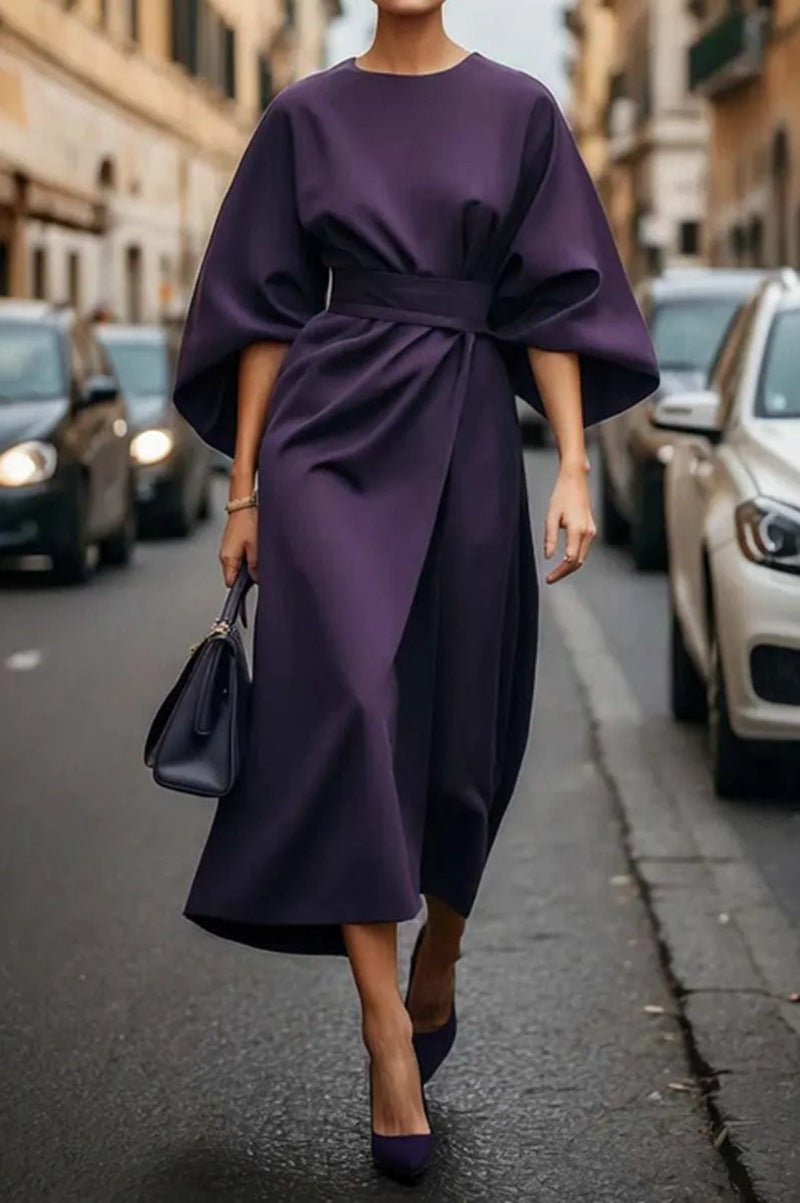 "Elegante zwarte midi-jurk met wijde mouwen, verfijnde tailleband en luxe stof, ideaal voor elke gelegenheid."