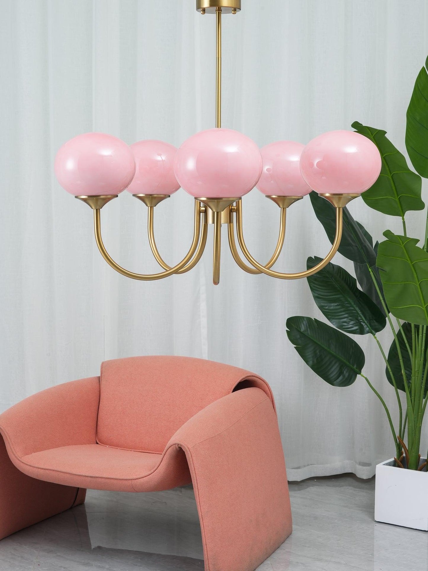 "Moderne kroonluchter met gouden afwerking en roze glazen kappen, geschikt voor LED verlichting in eigentijds interieur."