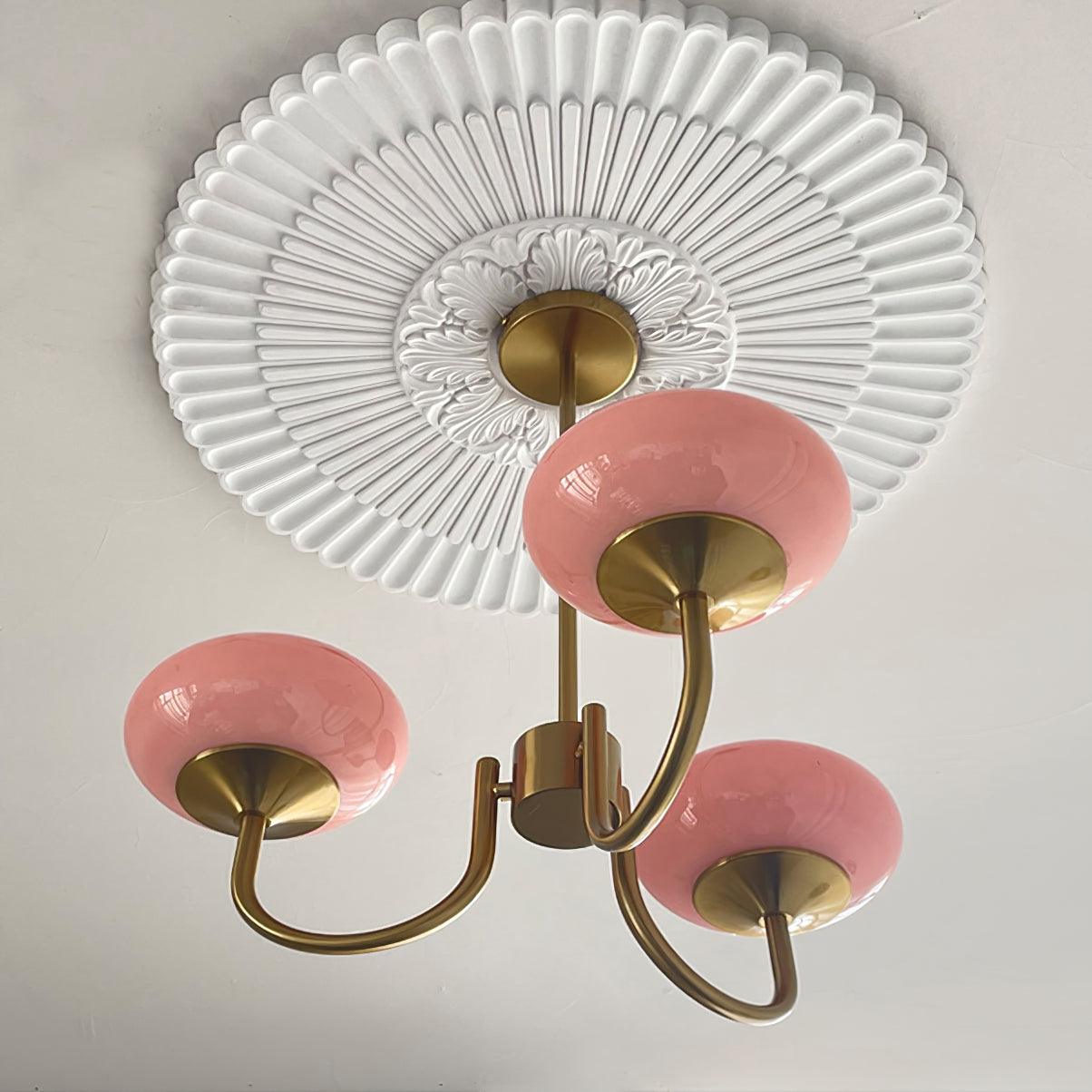 "Moderne kroonluchter met gouden afwerking en roze glazen kappen, geschikt voor LED verlichting in eigentijds interieur."