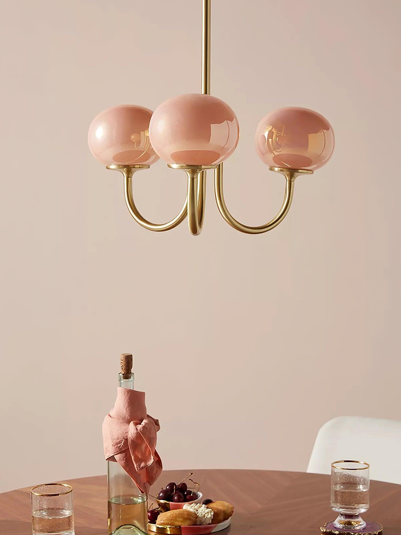 "Moderne kroonluchter met gouden afwerking en roze glazen kappen, geschikt voor LED verlichting in eigentijds interieur."