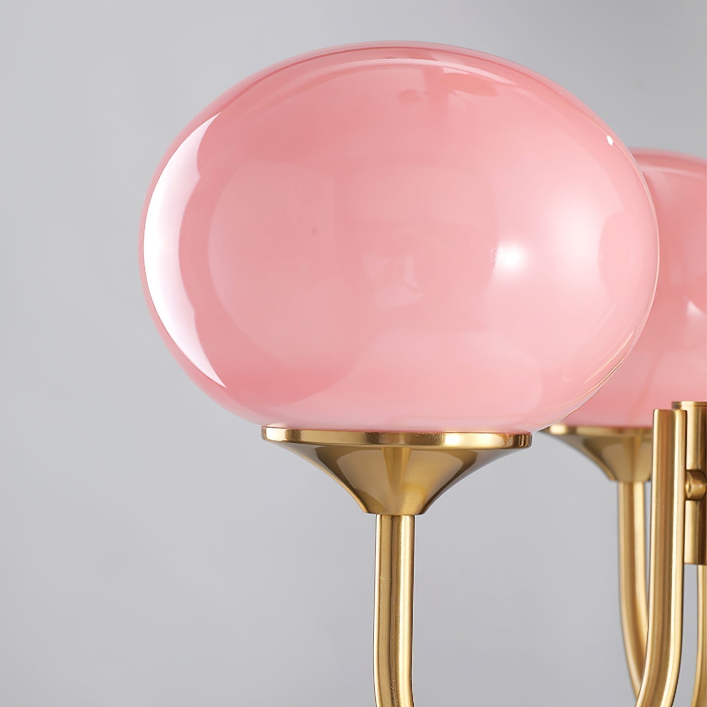"Moderne kroonluchter met gouden afwerking en roze glazen kappen, geschikt voor LED verlichting in eigentijds interieur."
