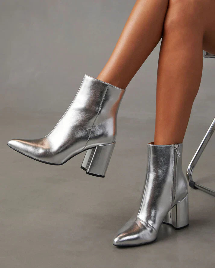 Zilveren metallic enkellaars met glamour blokhak, puntige neus en ritssluiting. Verhoog je stijl met deze elegante laarsjes.