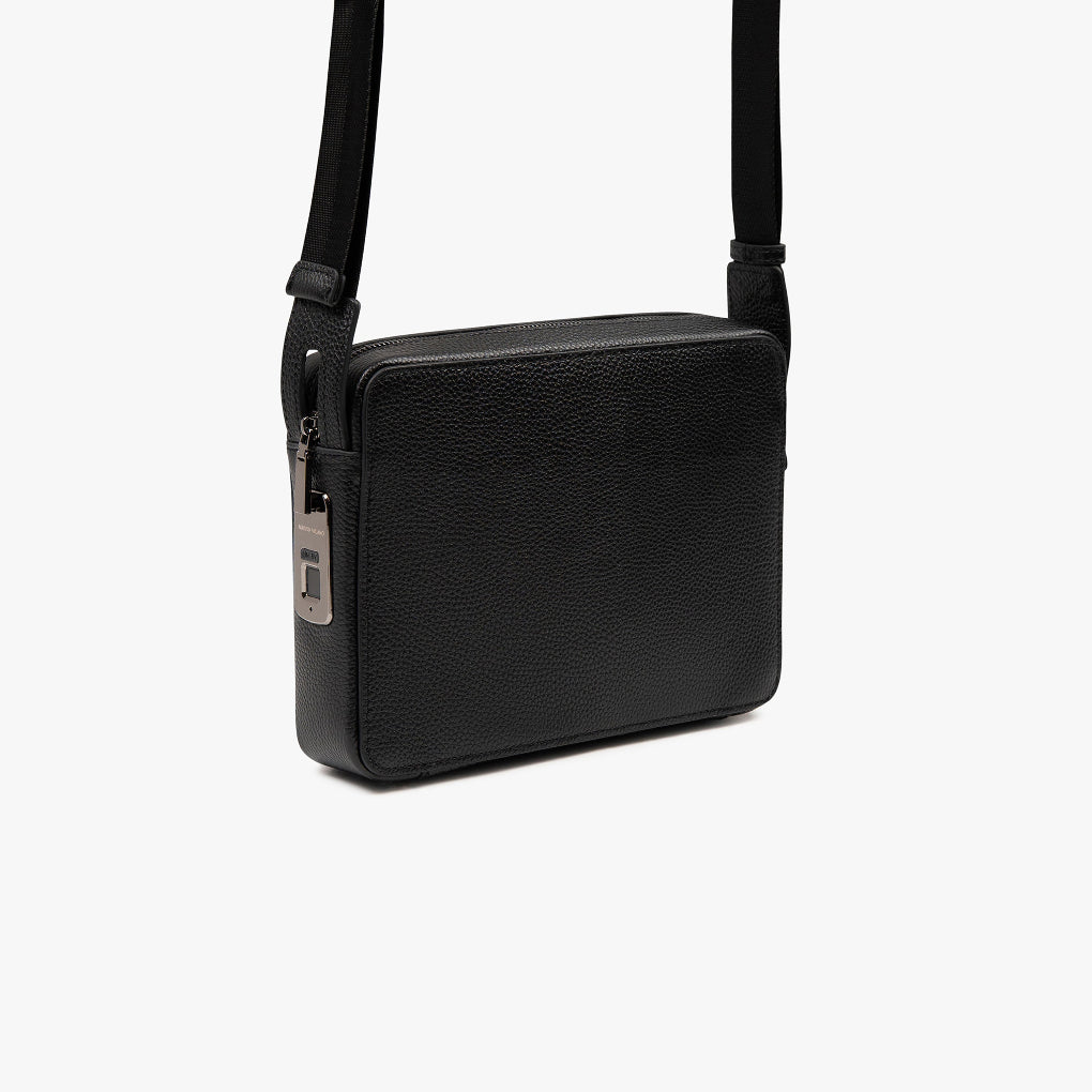 Unisex model draagt compacte, elegante schoudertas (mvb26) met vingerafdrukslot. Ideaal voor zakelijk en dagelijks gebruik.