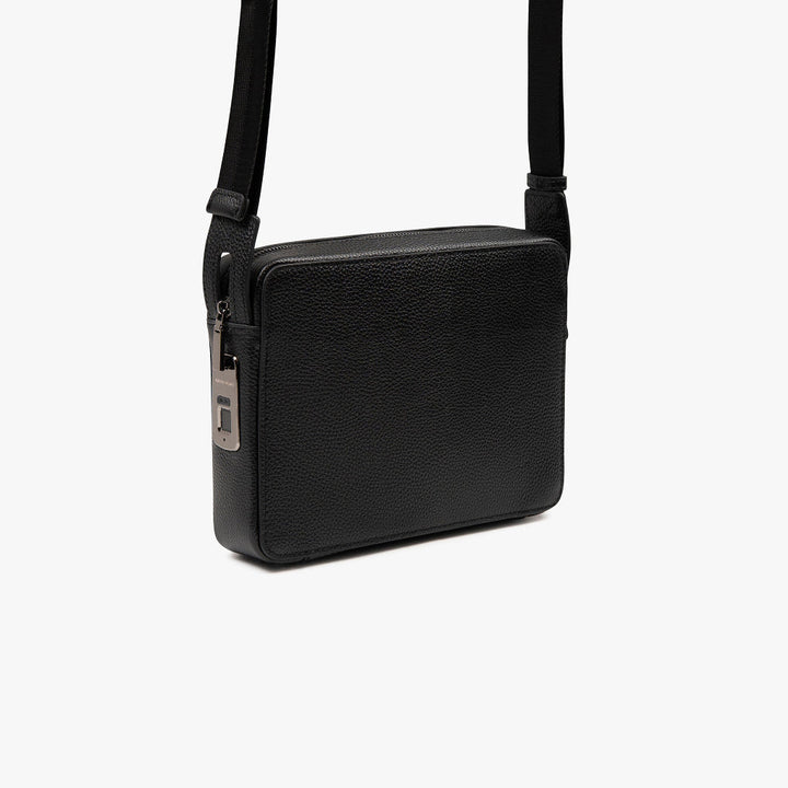 Unisex model draagt compacte, elegante schoudertas (mvb26) met vingerafdrukslot. Ideaal voor zakelijk en dagelijks gebruik.