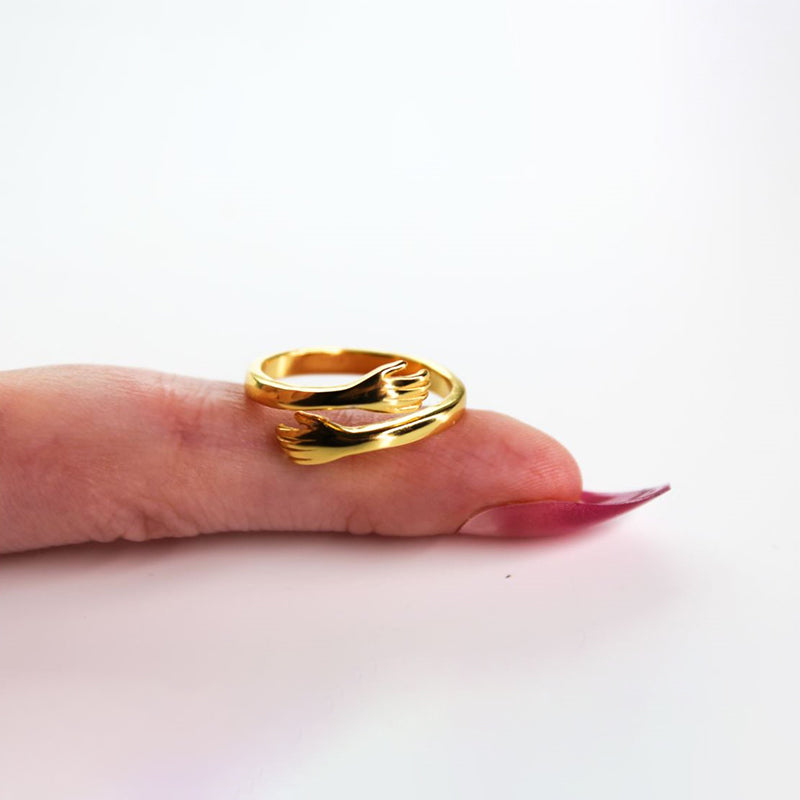 Goudkleurige dames omarmingsring, verstelbaar, met uniek omhelzend design. Een elegant liefdessymbool voor elke vrouw.