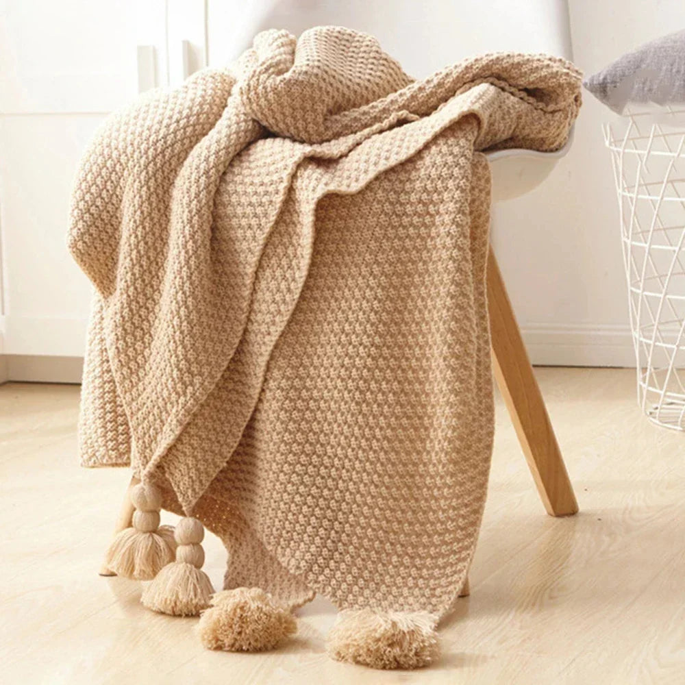 Gebreide wollen deken met decoratieve kwastjes, een stijlvolle en comfortabele plaid voor je interieur.