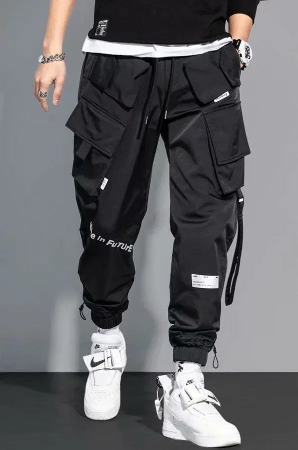 Model draagt een trendy heren cargo broek met meerdere zakken, perfect voor urban streetstyle.