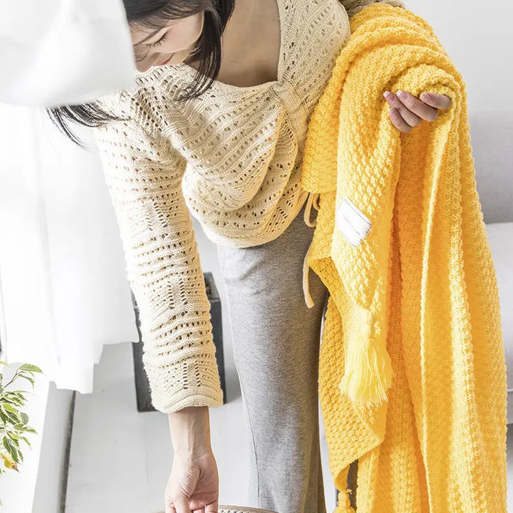 Veelzijdig gebreid wollen plaid met kwastjes; ideaal als deken, woonaccessoire of interieurdecoratie.