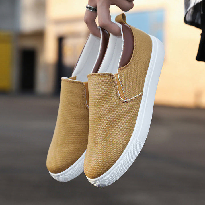 Zijkant van een grijze canvas heren slip-on schoen, met comfortabele zool en elastische instap.
