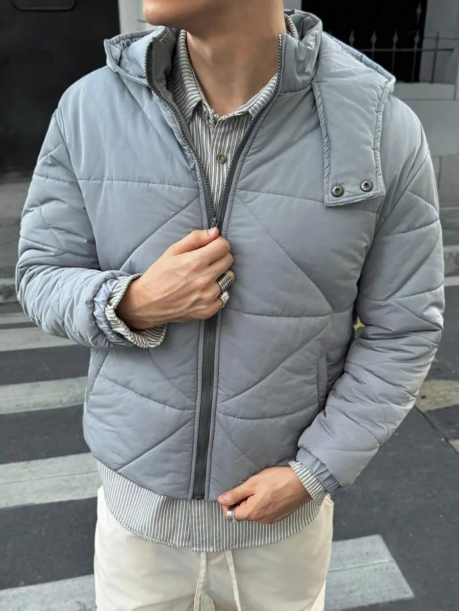 Grijs heren pufferjack met capuchon, ideaal voor koude winterdagen. Comfortabele heuplengte casual jas.