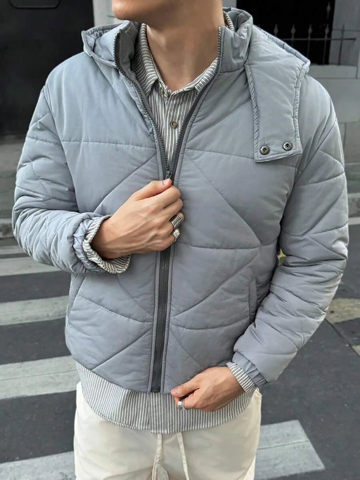 Grijs heren pufferjack met capuchon, ideaal voor koude winterdagen. Comfortabele heuplengte casual jas.