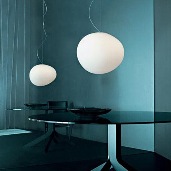 Strakke hanglamp in kiezelvorm, ideaal voor een modern interieur; witte, zwevende sfeerverlichting.