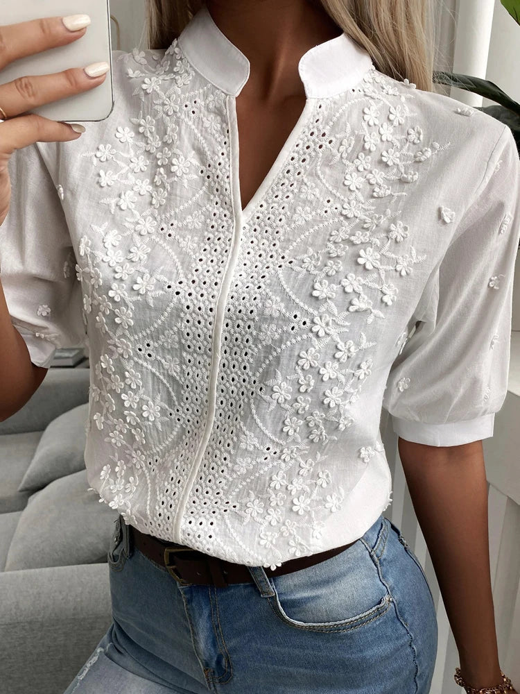 Witte damesblouse met V-hals en korte mouwen. Trendy zomer top met elegant bloemenborduursel.