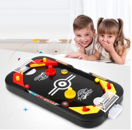 Lachende kinderen spelen met mini tafelhockey; een spannend behendigheidsspel en familiespel voor urenlang plezier.