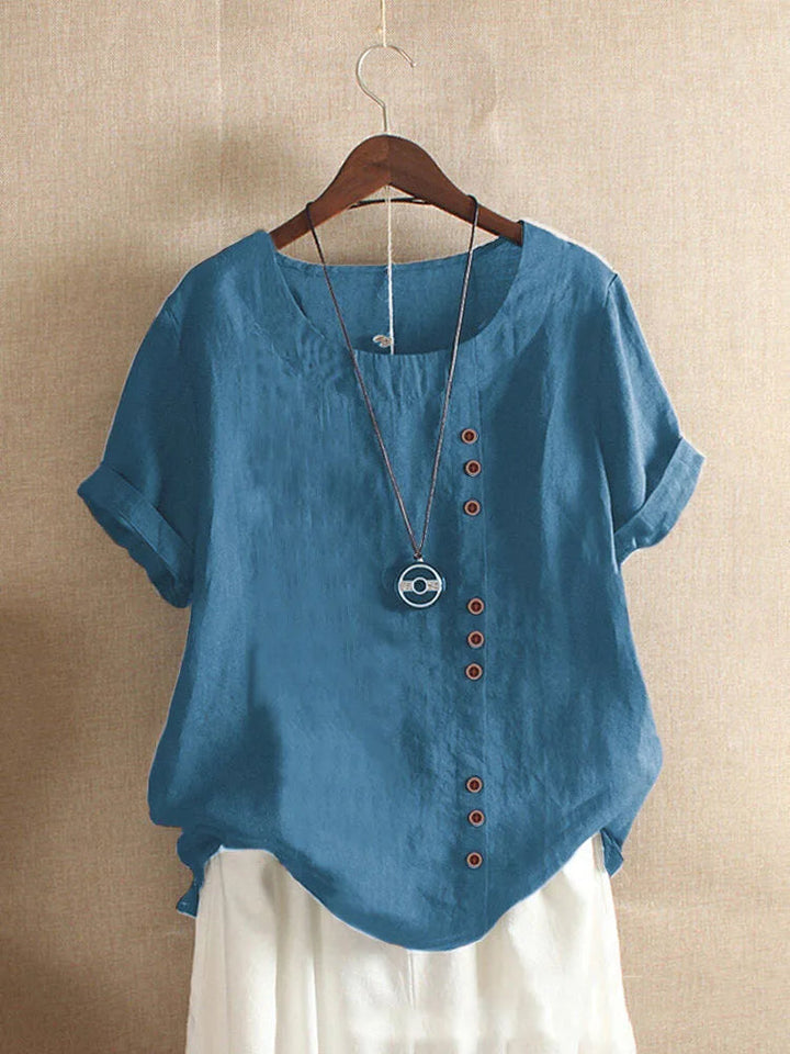 Luchtige losse pasvorm damesblouse met korte mouwen, knoopdetails en Peter Pan kraag. Comfort voor warme zomerdagen.