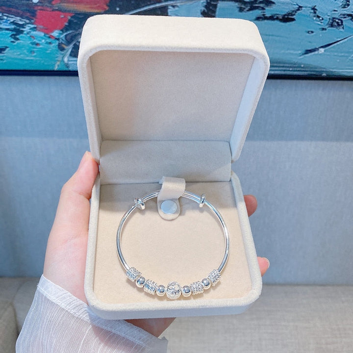 Damesarmband met elegante zilveren gelukskralen om de pols, een verfijnd mode-accessoire.
