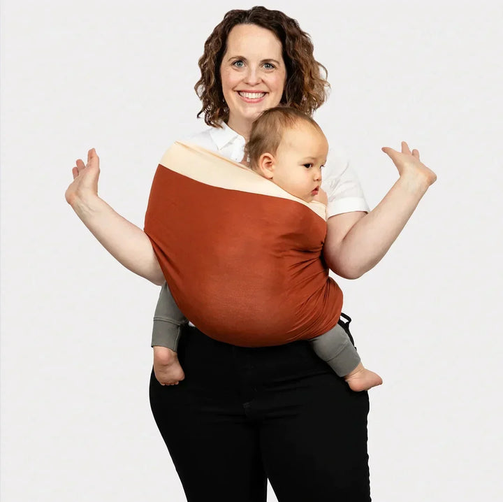 Ouder draagt pasgeboren baby handsfree in comfortabele, veilige draagdoek van biologisch katoen. Ergonomisch design.
