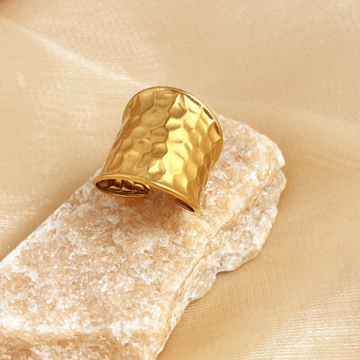 Detail van brede open unisex ring in goudkleurig edelstaal. Met uniek gehamerd watergolfpatroon, een stijlvol sieraad.