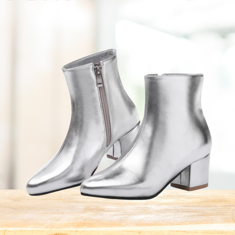 Achteraanzicht van glanzende zilveren dames enkellaarsjes. Comfortabele, stijlvolle en modieuze metallic laarsjes.
