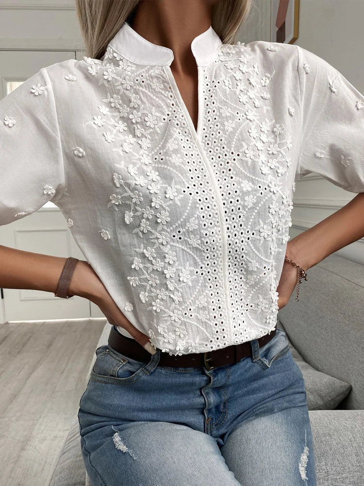 Trendy dames kleding: witte top met V-hals, korte mouwen en delicaat bloemenborduursel. Zomerstijl.