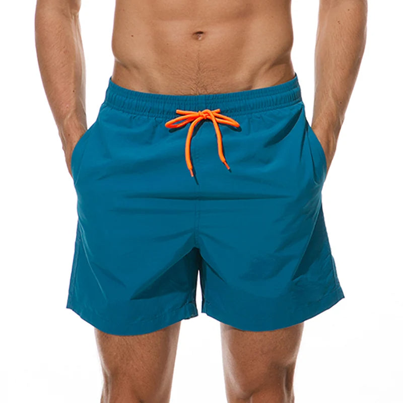 Jonge man draagt sportieve, sneldrogende heren zwemshort aan het strand, genietend van de zomer.