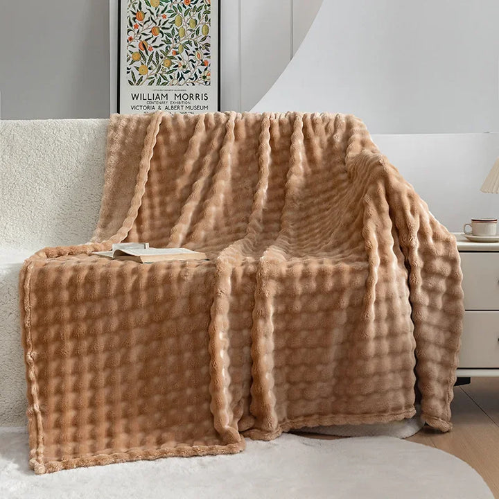 Gezellige PlushBubble flanellen woondeken gedrapeerd over een bank, voor stijlvolle huisdecoratie en warmte.