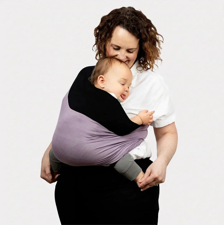 Tevreden baby slaapt veilig in ergonomische multifunctionele draagzak. Biologisch katoen voor pasgeboren comfort.
