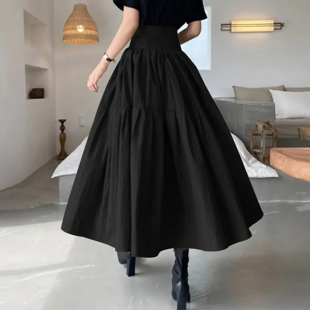 Dames maxi rok met plooi en elastische taille, afgebeeld in een zomerse setting, comfortabel en elegant.