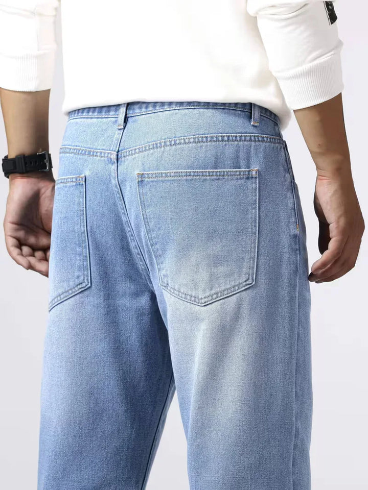 Close-up van de vijf zakken op een petrol blauwe heren loose fit jeans met rechte pijp.