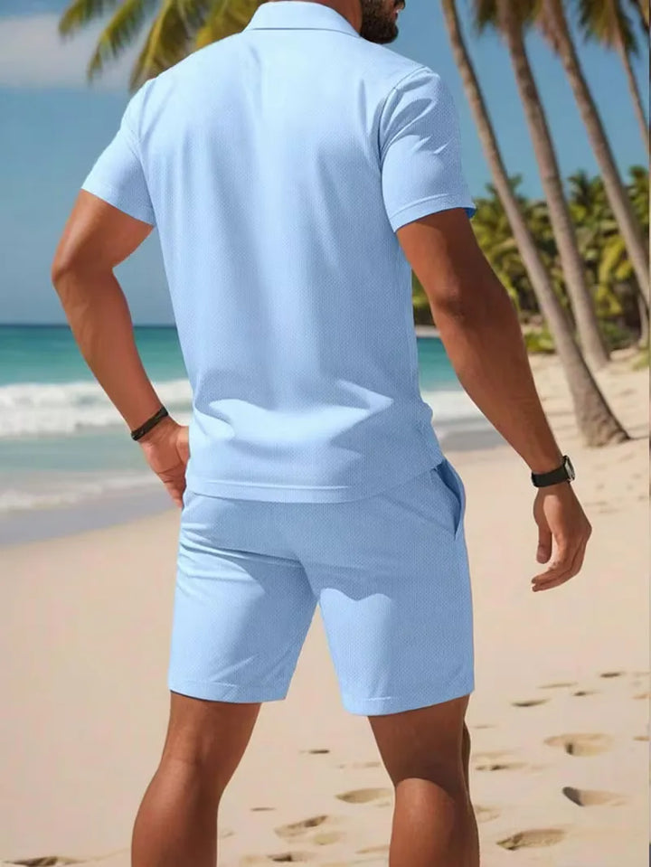 Heren tweedelige zomerset: lichtblauwe polo V-hals, bijpassende witte shorts, ideaal voor strand.
