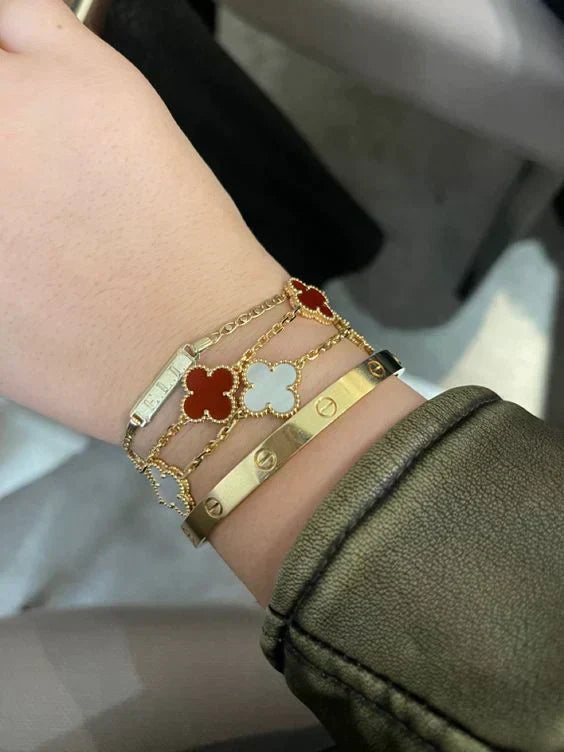 Detailopname van een unieke damesarmband met rode klaver en goudkleurige details, Marrakech-stijl.