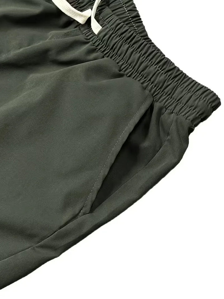 Detailopname van de ruime zijzakken op een heren taps toelopende cargo broek met elastische boorden.