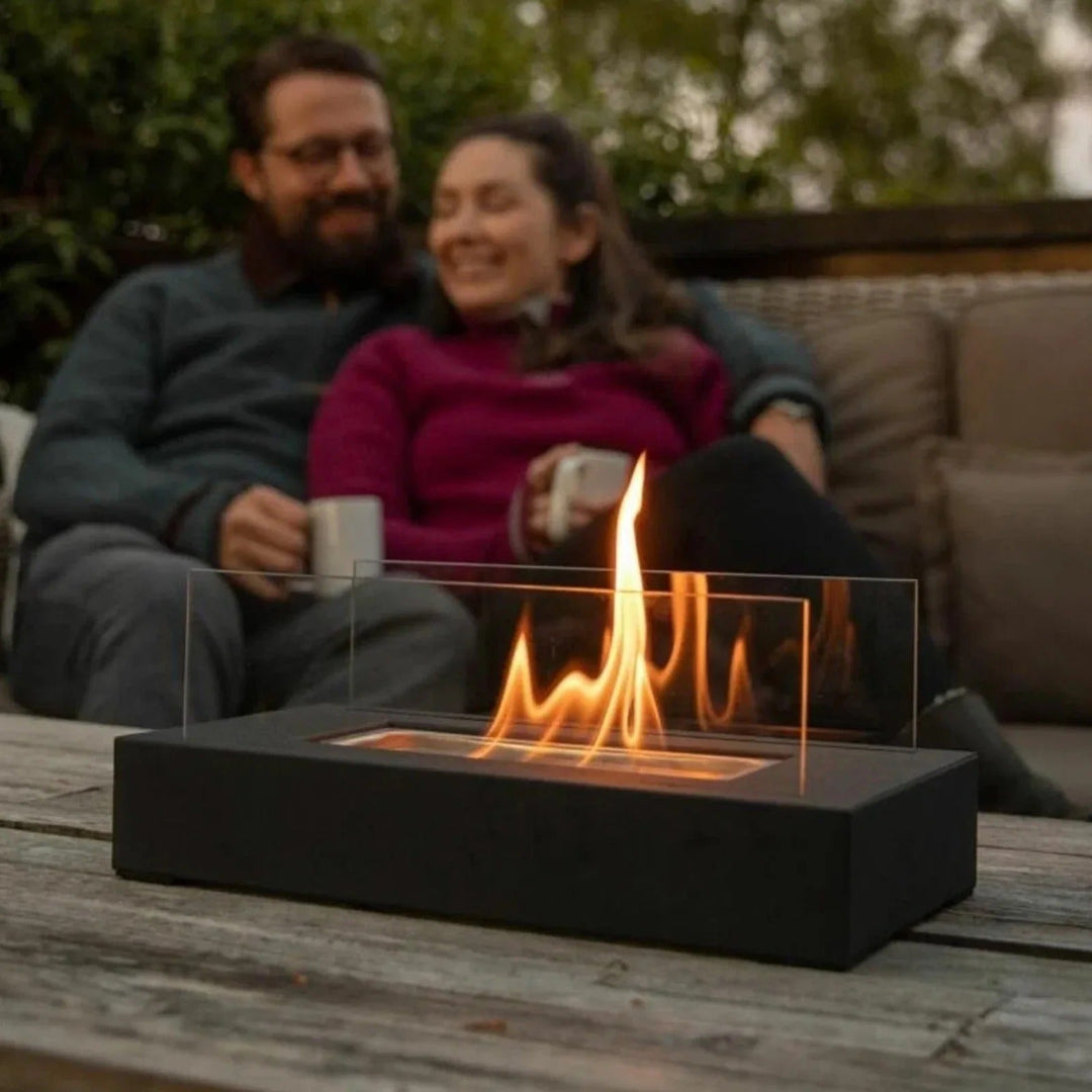 Luxe Serene Flame bio-ethanol sfeerhaard voor buiten, modern design met glas en beton, creëert warme sfeer op terras.