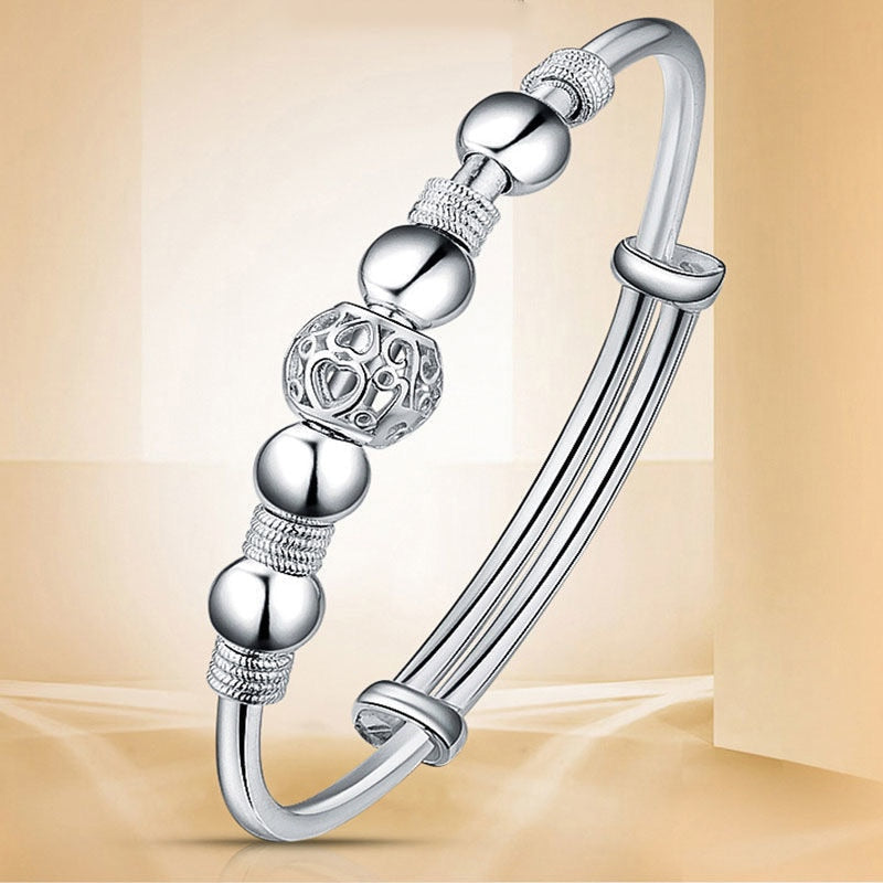 Close-up van de damesarmband met gedetailleerde verzilverde gelukskralen, een trendy sieraad.