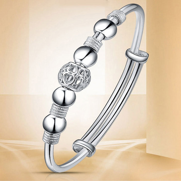 Close-up van de damesarmband met gedetailleerde verzilverde gelukskralen, een trendy sieraad.