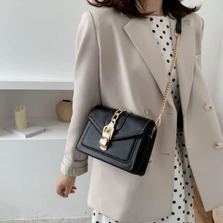 Gedetailleerde textuur van de zwarte PU leren dames sling bag met glanzende kettingdetails.