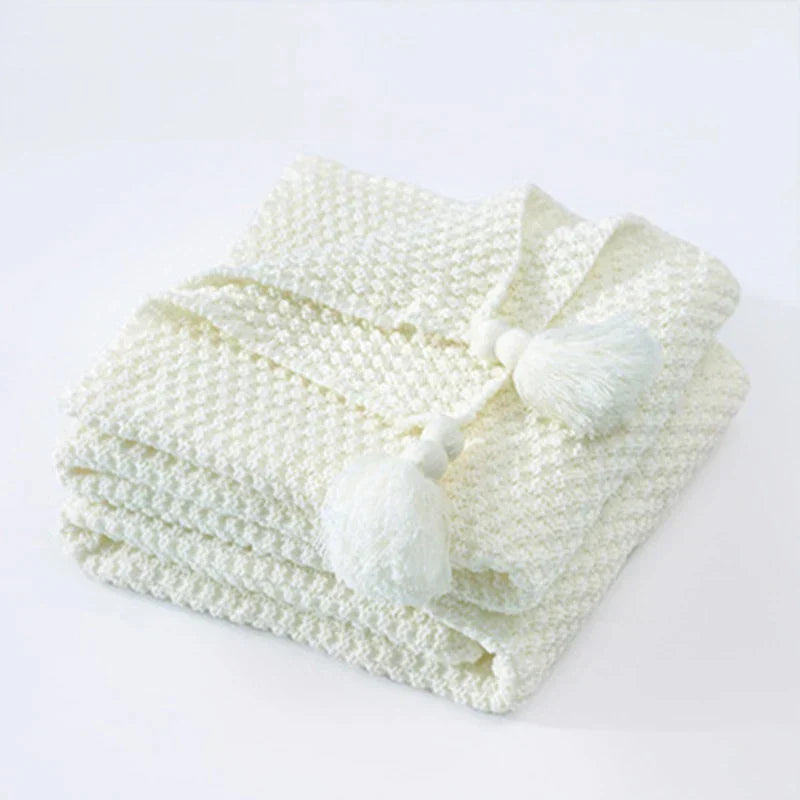 Warme gebreide wollen deken van NordicCozy met kwastjes, creëert sfeer en comfort in huis.