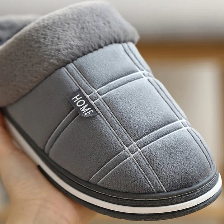 Man draagt comfortabele geruite instappers, warme pantoffels voor ontspanning thuis.