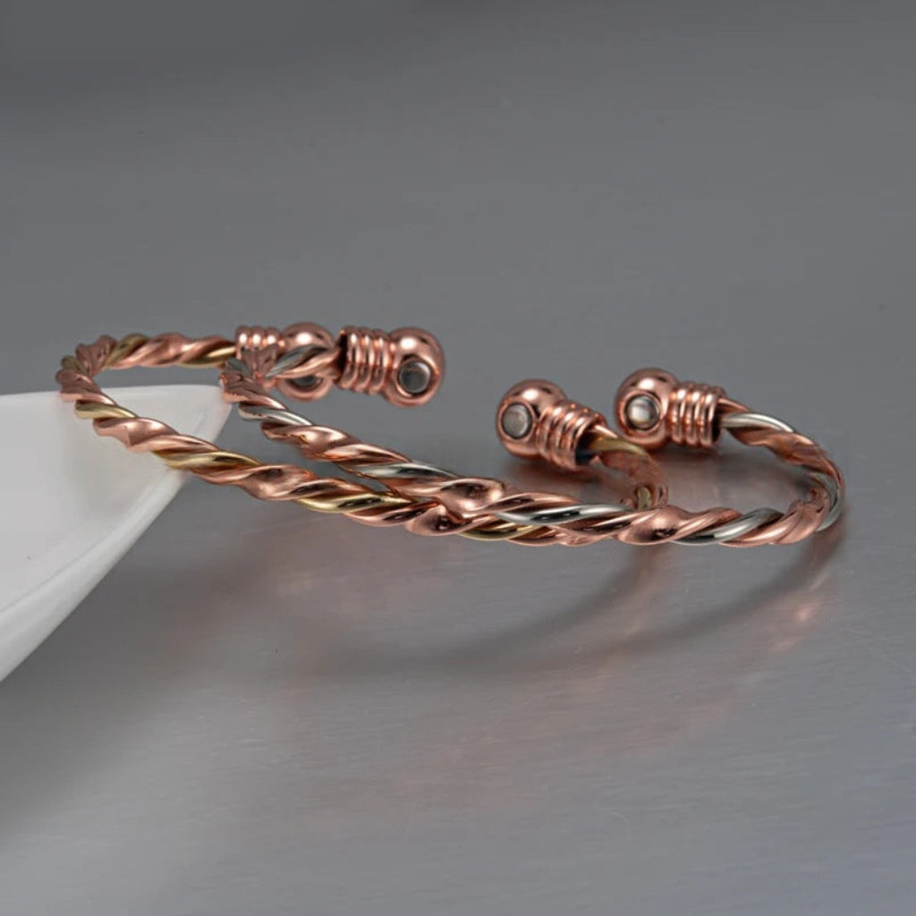 Gedraaide koperen armband met magnetische therapie; unisex wellness sieraad voor polscomfort. Elegante bangle in roségoud tint.